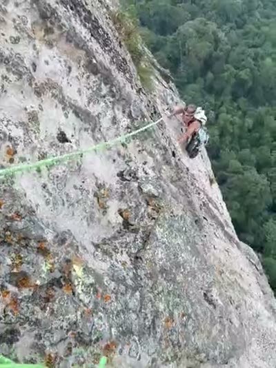 From the belayer's stance — a pitch of rope out, jungle and sea below.